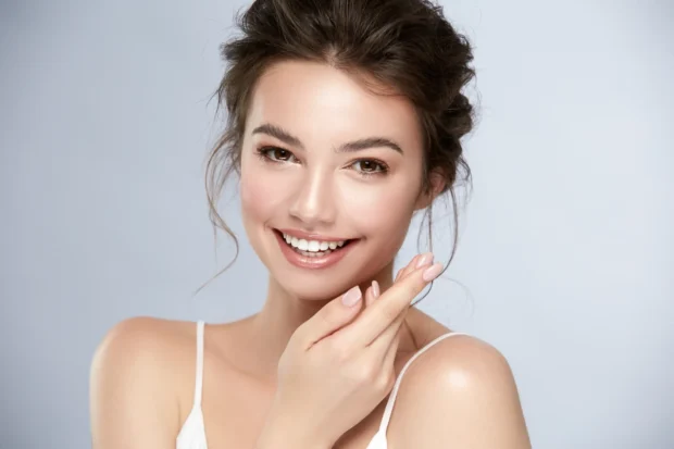 Smiling woman with clear, glowing skin showcasing healthy complexion and natural beauty after professional skincare treatment.